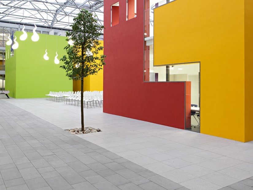 Gepflanzte Bäume und die Farbgestaltung lockern die Atmosphäre im Innenhof der Schule auf.