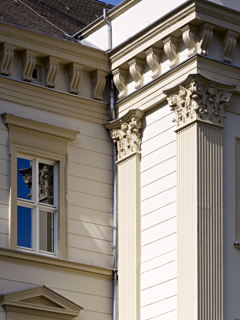 Bei der Detailbetrachtung fallen die korinthischen Kapitelle und die Kannelierungen der Pilaster ins Auge. Licht und Schatten schaffen eine lebendige Optik.