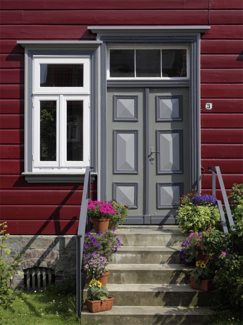 Das Betongrau der Haustür harmoniert sowohl mit den übrigen Farbgebungen als auch mit dem Sockel aus Naturstein.