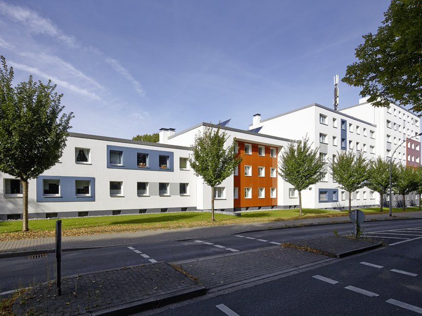 Nachher: Im Rahmen der Sanierung wurde die gesamte Fassade modernisiert. Graue Fensterbänder und blaue Fenstergewänder gliedern und schaffen Blickpunkte.