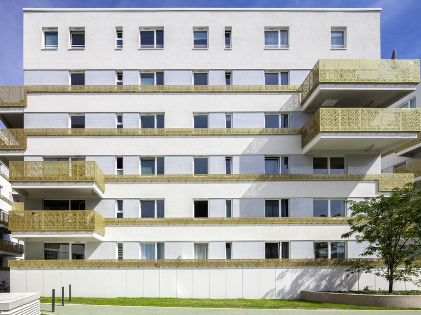 Die Akzentstreifen aus pixelartig ausgestanztem goldfarbenen Blech – mal höher als Balkonbrüstung, mal schmaler als Fensterbrüstung - lassen den Gebäudekomplex einladend wirken.
