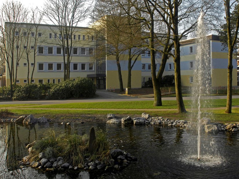 Dieses Gebäude auf dem großen Klinikgelände in Marl suggeriert dem Betrachter eine durch die sanfte Farbgebung gewisse Leichtigkeit. Die Sandtöne des Weges, das Blau von Wasser und Himmel spiegeln sich in der Architektur wider.