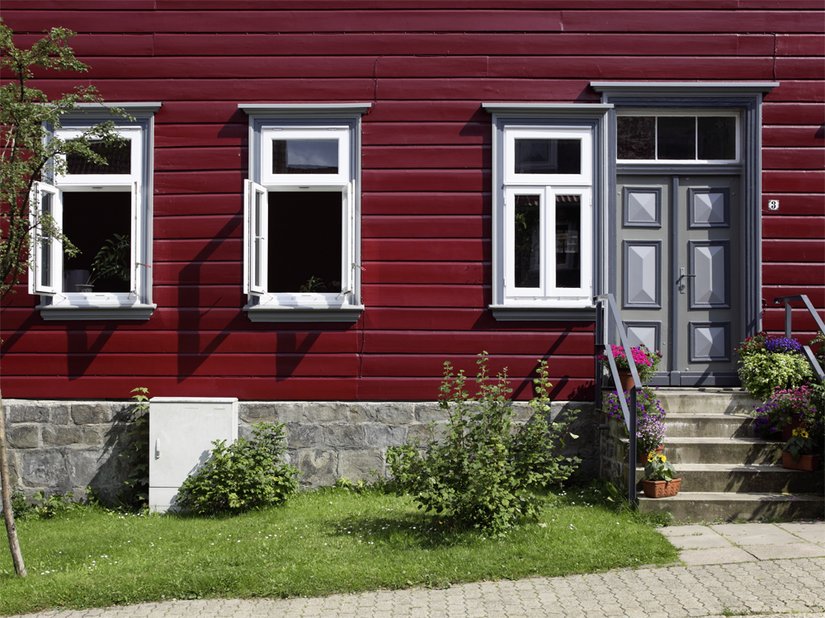 Besonders die Fensterbekleidungen setzen sich signifikant vom Ochsenblutrot der Fassade ab.