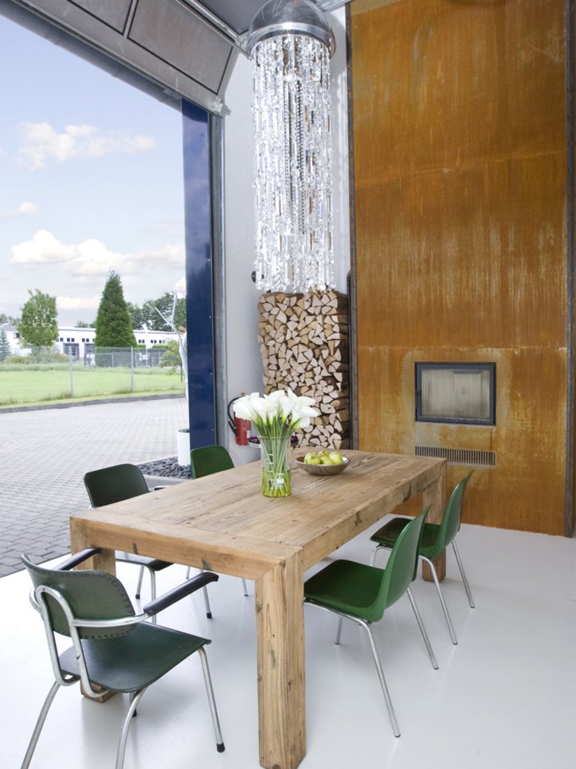 Der warme Holztisch markiert zusammen mit dem in der Wand eingelassenen Kamin und seinem rostfarbenen Paneel das Zentrum des Lofts.