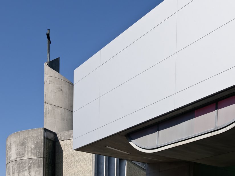 Die „vertikale“ Fassade wirkt durch die homogene Verkleidung mit silbergrauen Aluminiumplatten fast wie eine Karosserie.