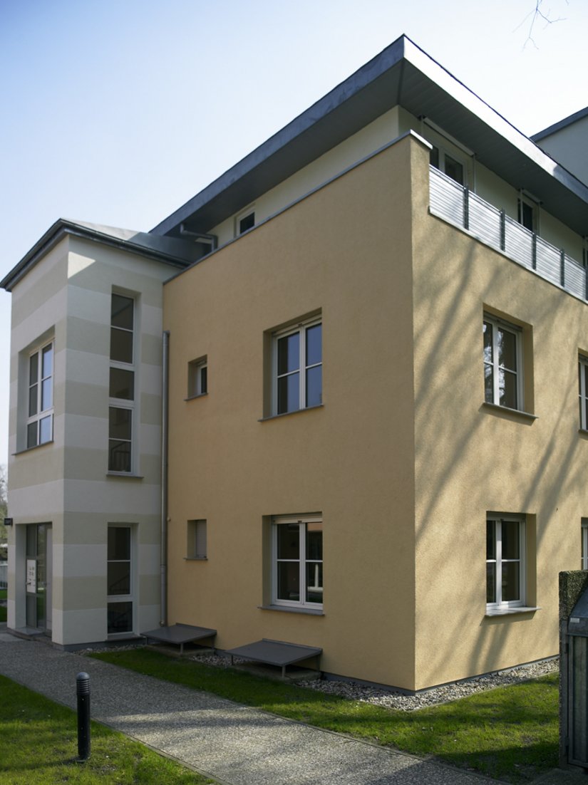 Die Streifenfassaden bilden die Gleichheit, die einheitliche Ordnung und das neben der mediterranen Farbigkeit die Siedlung bestimmende Element. Haus 4 (farbgleich mit Haus 1) – Fassade: 15.12.12, Dachgeschoss, Fassadenband: 06.06.06, Fassadenband: 03.03.03, Balkonbrüstung: Trespa A 03.4.0